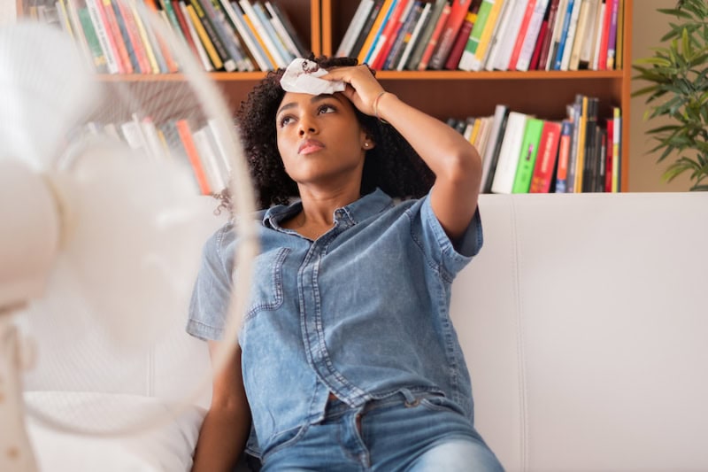 Common Summer AC Problems and Solutions. Woman sweating and trying to refresh at home.